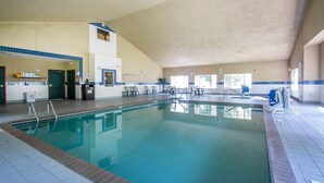 An indoor swimming pool with a tiled deck, a lifeguard chair, and a small seating area with chairs. - Quality Inn & Suites East Troy I-43 (East Troy)