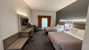 A hotel room with two beds, a desk with a chair, a television, and a window with curtains.