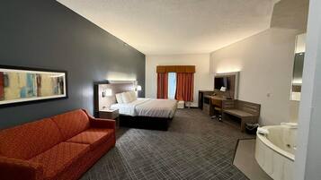 Ein Hotelzimmer mit Bett, Schreibtisch, Stuhl, Sofa, Badezimmer und einem Bild an der Wand.