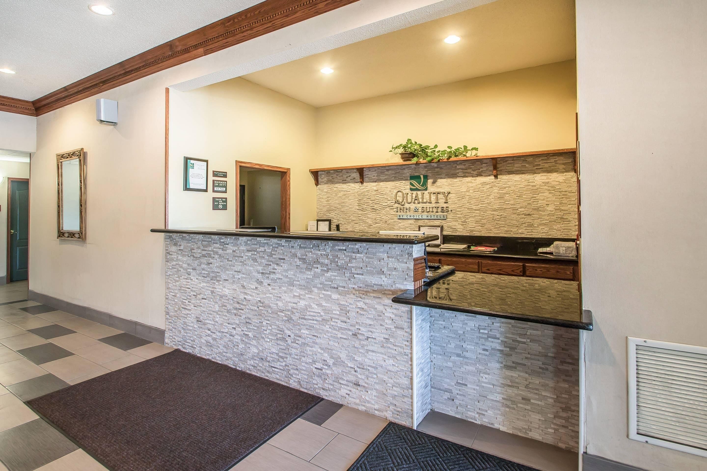 A reception area with a stone wall, a reception desk, a mirror, and a plant.