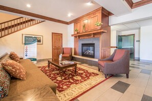 A spacious living room with a fireplace, a sofa set, a coffee table, and a patterned rug. - Quality Inn & Suites East Troy I-43 (East Troy)