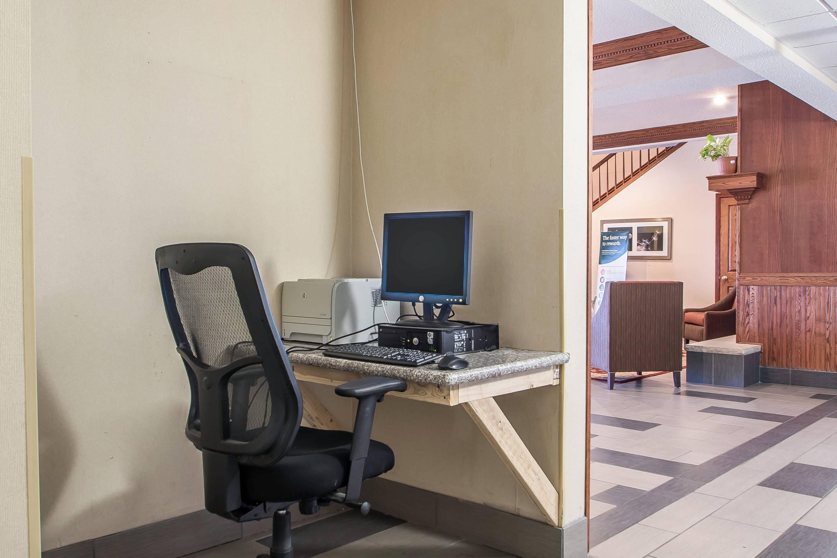 A workspace with a desk, chair, computer, and printer.
