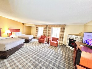 A hotel room with two beds, a TV, a fireplace, and a checkered carpet.
