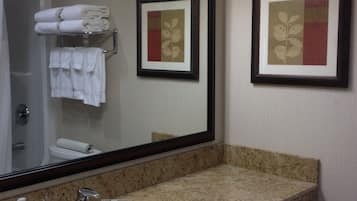 Un baño con lavamanos de encimera de granito, un espejo y una obra de arte enmarcada en la pared.