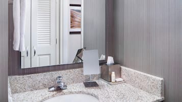 A bathroom with a granite countertop, a sink, a mirror, and a towel rack.