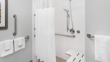 A modern bathroom with a shower, grab bars, and a white towel rack.