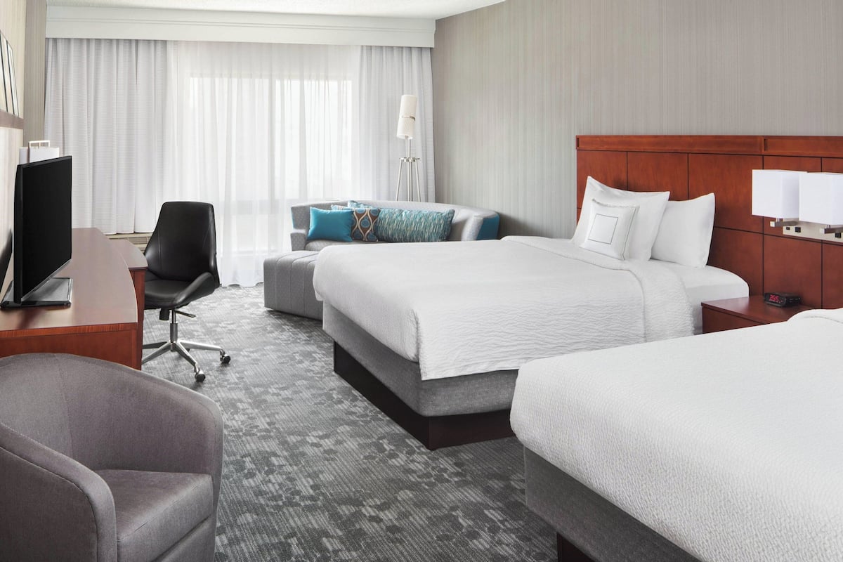 Une chambre d’hôtel avec un grand lit, un bureau équipé d’un ordinateur, une chaise et un téléviseur.