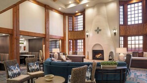 A spacious lobby with a large seating area, a fireplace, and a high ceiling with exposed beams. - Courtyard by Marriott Farmington (Farmington)