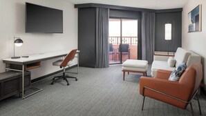 A hotel room with a flat-screen TV, a desk with a chair, a sofa, and a balcony with a view. - Courtyard by Marriott Farmington (Farmington)