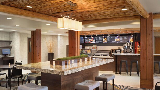A modern kitchen with a central island, bar stools, and a seating area with a round table. - Courtyard by Marriott Farmington (Farmington)