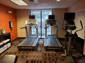 A fitness room with two treadmills, a stationary bike, and a TV screen. - Courtyard by Marriott Farmington (Farmington)