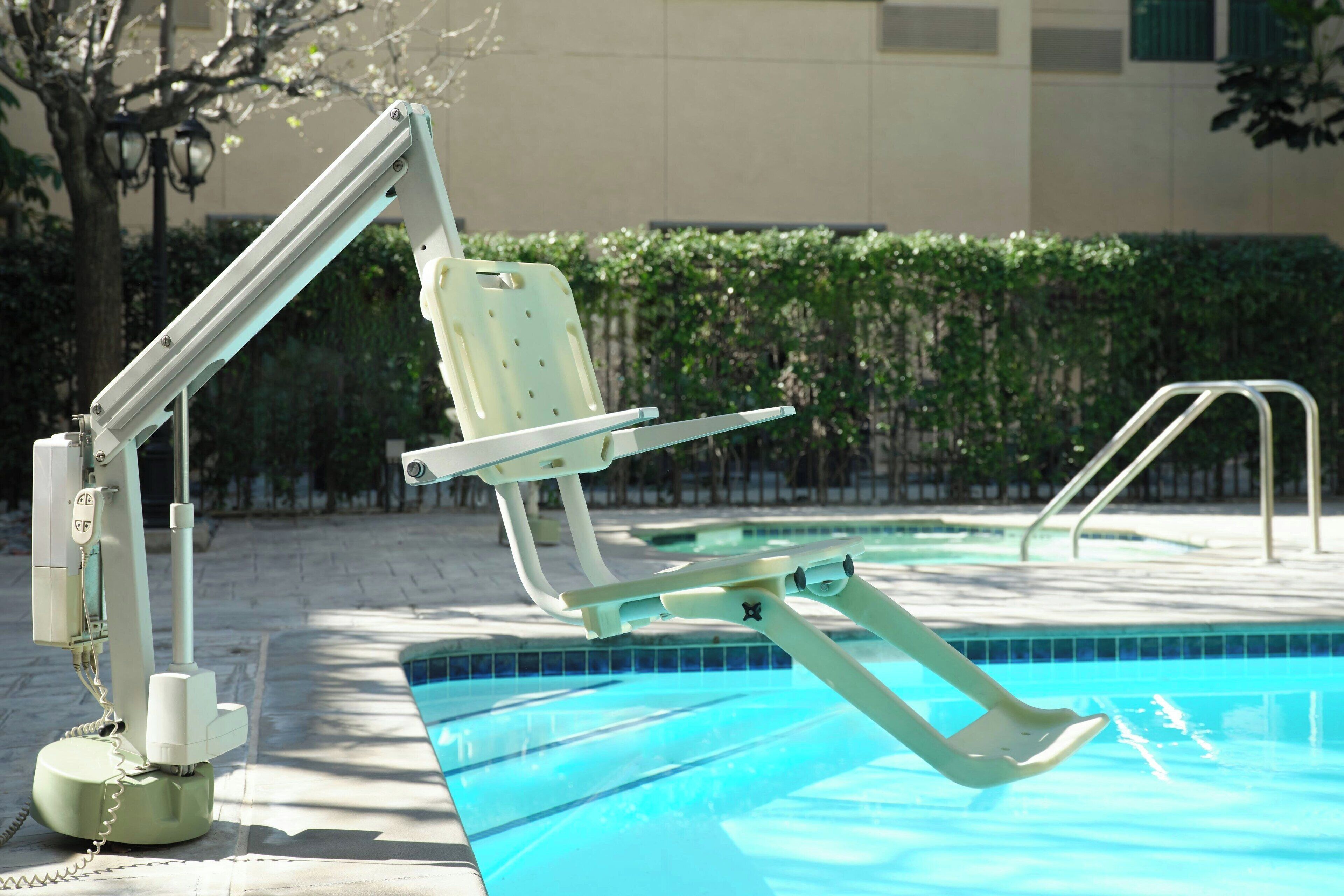 Area piscina con una sdraio, una scala per la piscina e una postazione di salvataggio.