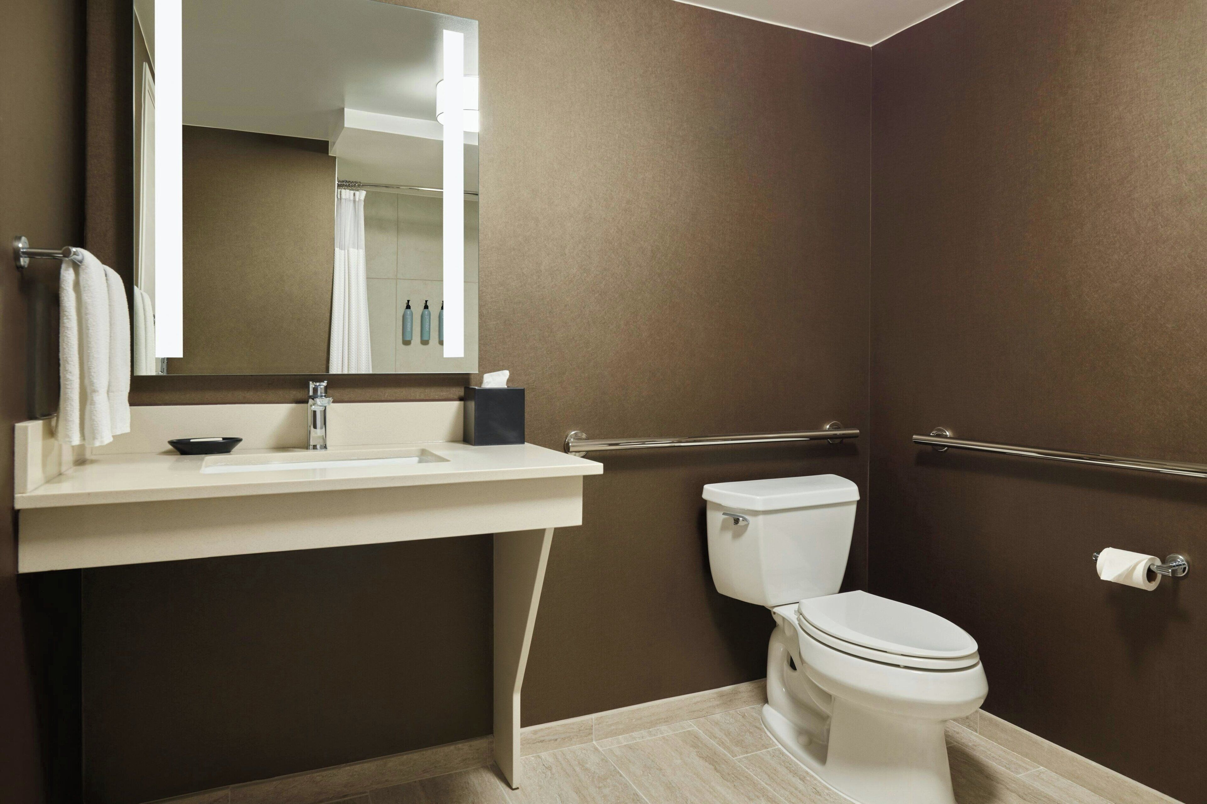 A modern bathroom with a white sink, mirror, and toilet.