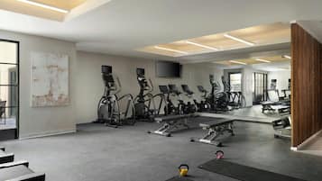 Un gimnasio moderno con cintas de correr, bicicletas estáticas y pesas libres.