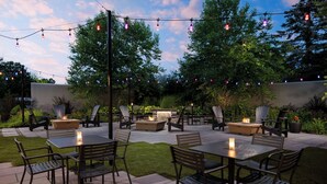 An outdoor patio area with a fire pit, seating, and string lights. - Courtyard by Marriott Concord (Concord)
