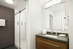 A modern bathroom with a glass shower enclosure, a sink with a mirror, and a towel rack. - Courtyard by Marriott Concord (Concord)