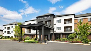 A Courtyard by Marriott hotel with a covered entrance, brick and white exterior, and landscaped gardens. - Courtyard by Marriott Concord (Concord)