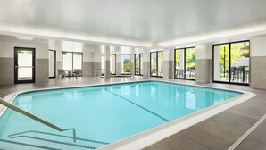 An indoor swimming pool with clear blue water, surrounded by large windows and a tiled floor. - Courtyard by Marriott Concord (Concord)