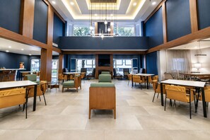 A spacious hotel lobby with multiple seating areas, a central fireplace, and large windows providing natural light. - Courtyard by Marriott Monterrey Airport (Apodaca)