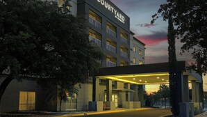 Um hotel Courtyard by Marriott com design moderno, com entrada coberta e várias varandas.