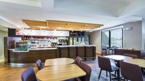 A modern restaurant with a bar area, wooden tables, and bar stools. - Courtyard by Marriott Rocky Mount (Rocky Mount)