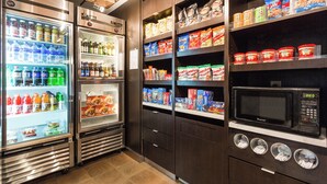 A self-service food station with refrigerated beverage dispensers, snack shelves, and a microwave. - Courtyard by Marriott Rocky Mount (Rocky Mount)