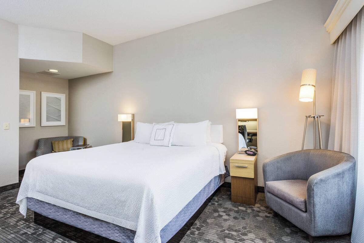 Une chambre d’hôtel avec un grand lit, une chaise, un bureau et une lampe.