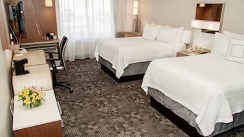 A hotel room with two beds, a desk with a telephone, and a chair.