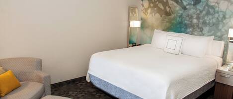 Een hotelkamer met een groot bed, een stoel, een nachtkastje en een muur met een reliëf muurschildering.