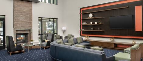 A modern living room with a sectional sofa, a fireplace, a flat-screen TV, and a large window.