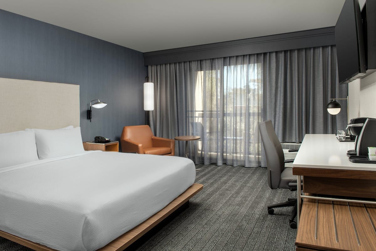 Een hotelkamer met een groot bed, een bureau met stoel, een klein tafeltje en een televisie.