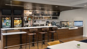 A modern bar area with a long counter, multiple stools, and a seating area with a table.