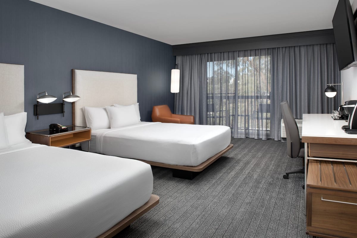 Een hotelkamer met twee bedden, een bureau, een stoel en een televisie.