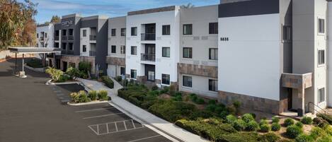 A modern multi-story hotel with a courtyard, parking, and landscaped areas.
