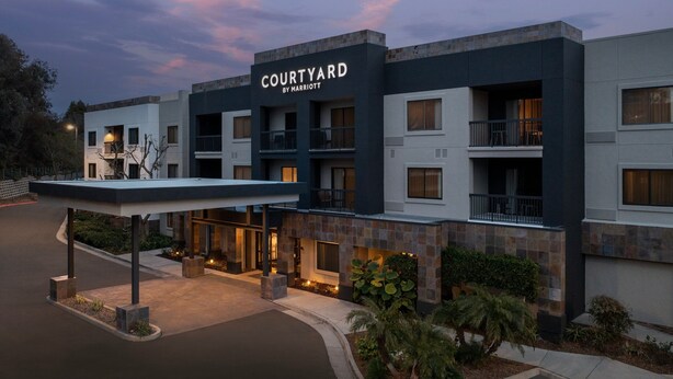 A multi-story hotel with a modern design, featuring a covered entrance area and multiple balconies.
