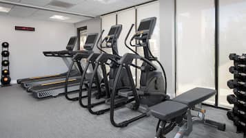 A gym with treadmills, a bench, and a wall-mounted digital clock.