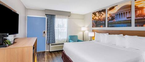 Une chambre d’hôtel avec un grand lit, un bureau doté d’un téléviseur à écran plat, une chaise, une lampe et une fenêtre avec des rideaux.