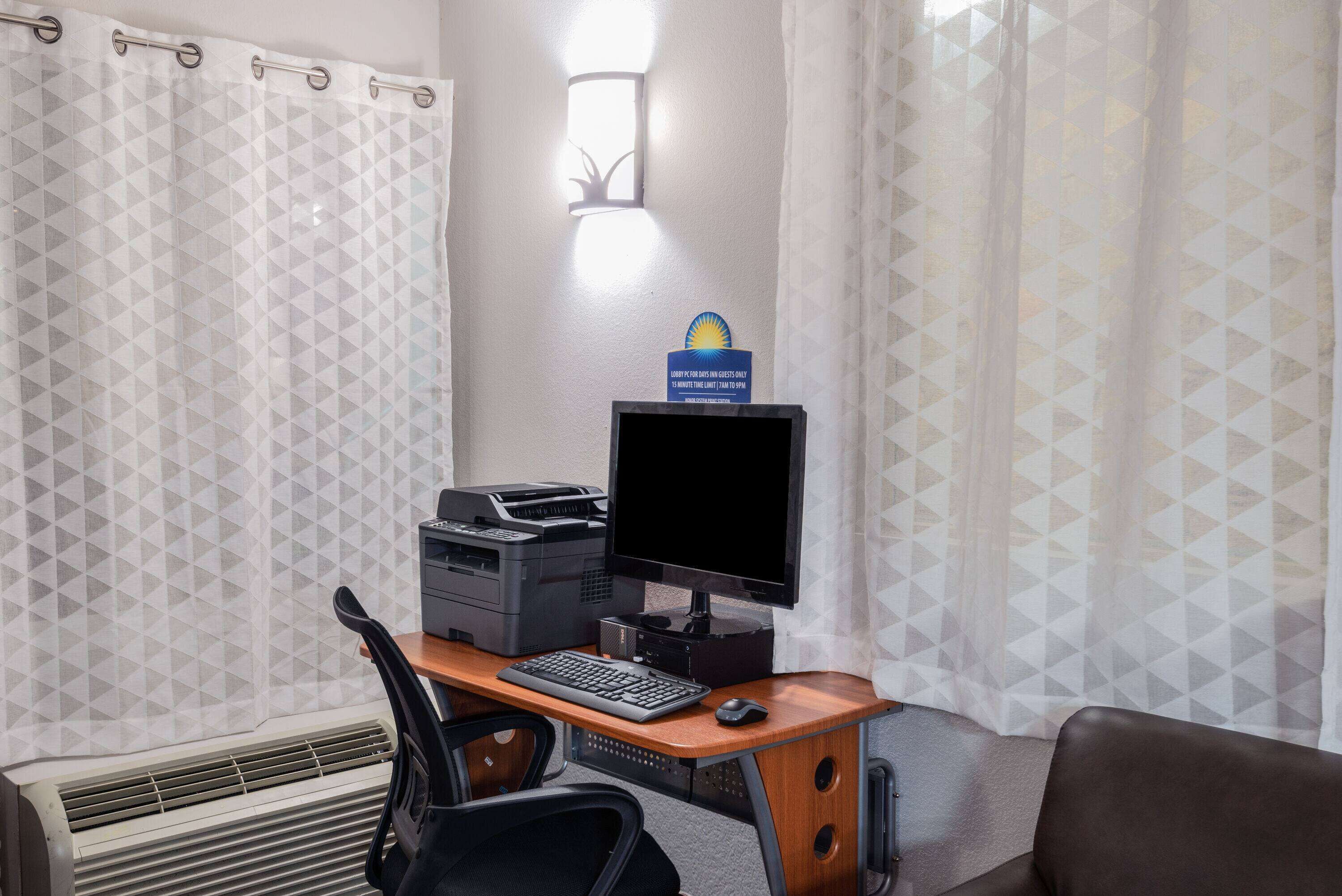 Una camera d'albergo con scrivania, computer, stampante e condizionatore d'aria.