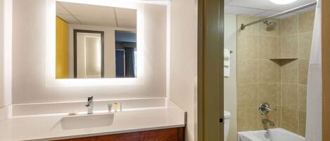 A bathroom with a white sink, mirror, and a shower area.