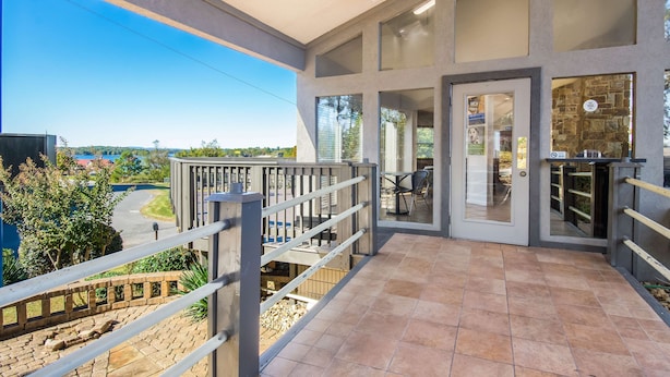A spacious balcony with a clear view of the surrounding area, a modern entrance with glass doors, and a stone wall feature. - Motel 6 Hot Springs, AR (Hot Springs)