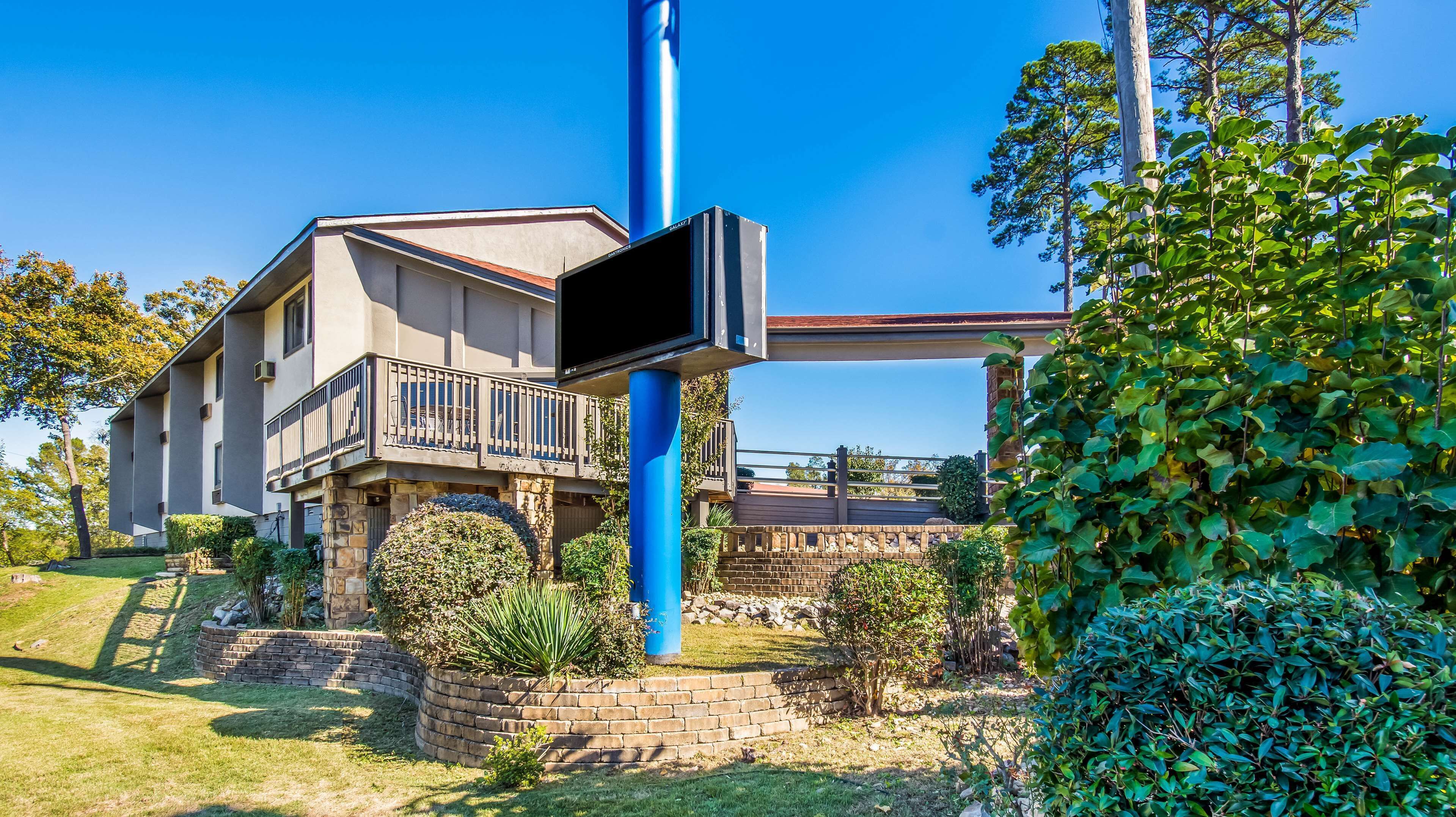 Une maison moderne à deux étages, dotée d’un balcon, d’un mur de soutènement en pierre et d’un jardin bien entretenu.