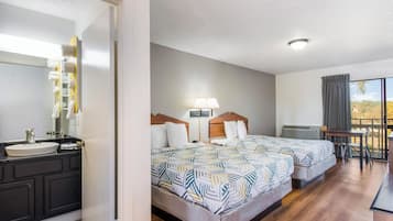 A hotel room with a bed, bedside table, lamp, and a view of the outdoors.