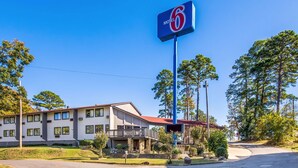 A motel with a prominent '6' sign, a two-story building with a red roof, and a landscaped front yard. - Motel 6 Hot Springs, AR (Hot Springs)