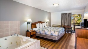 A hotel room with a large bed, a desk, a chair, a TV, a bathroom with a bathtub, and a window with curtains. - Motel 6 Hot Springs, AR (Hot Springs)
