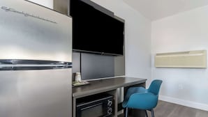 A compact kitchenette with a built-in refrigerator, microwave, and a flat-screen TV mounted above the counter. - Studio 6 Suites Madera, California - Yosemite (Madera)