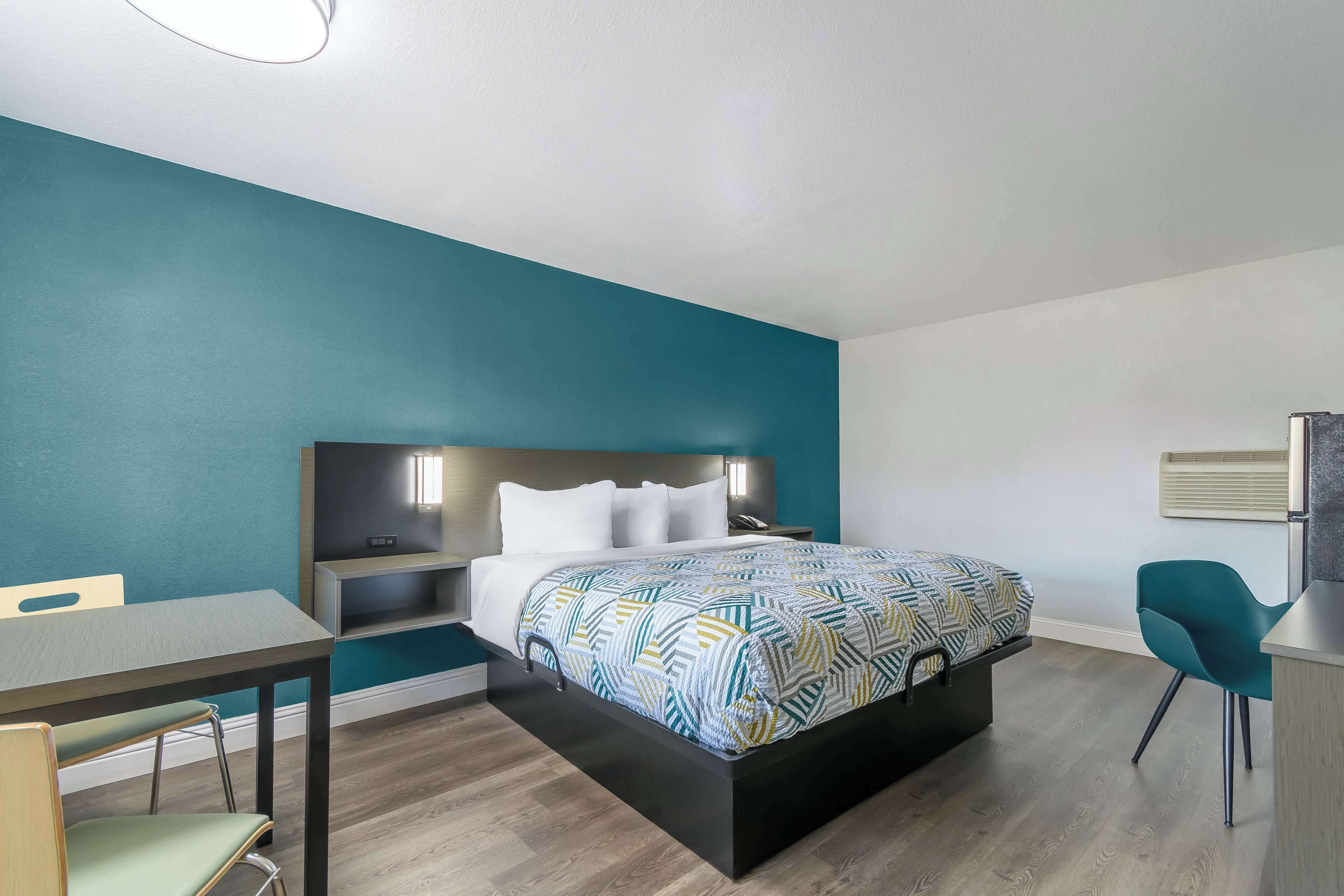 A modern bedroom with a bed, bedside tables, a desk, and a chair.