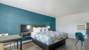 A modern bedroom with a bed, bedside tables, a desk, and a chair.