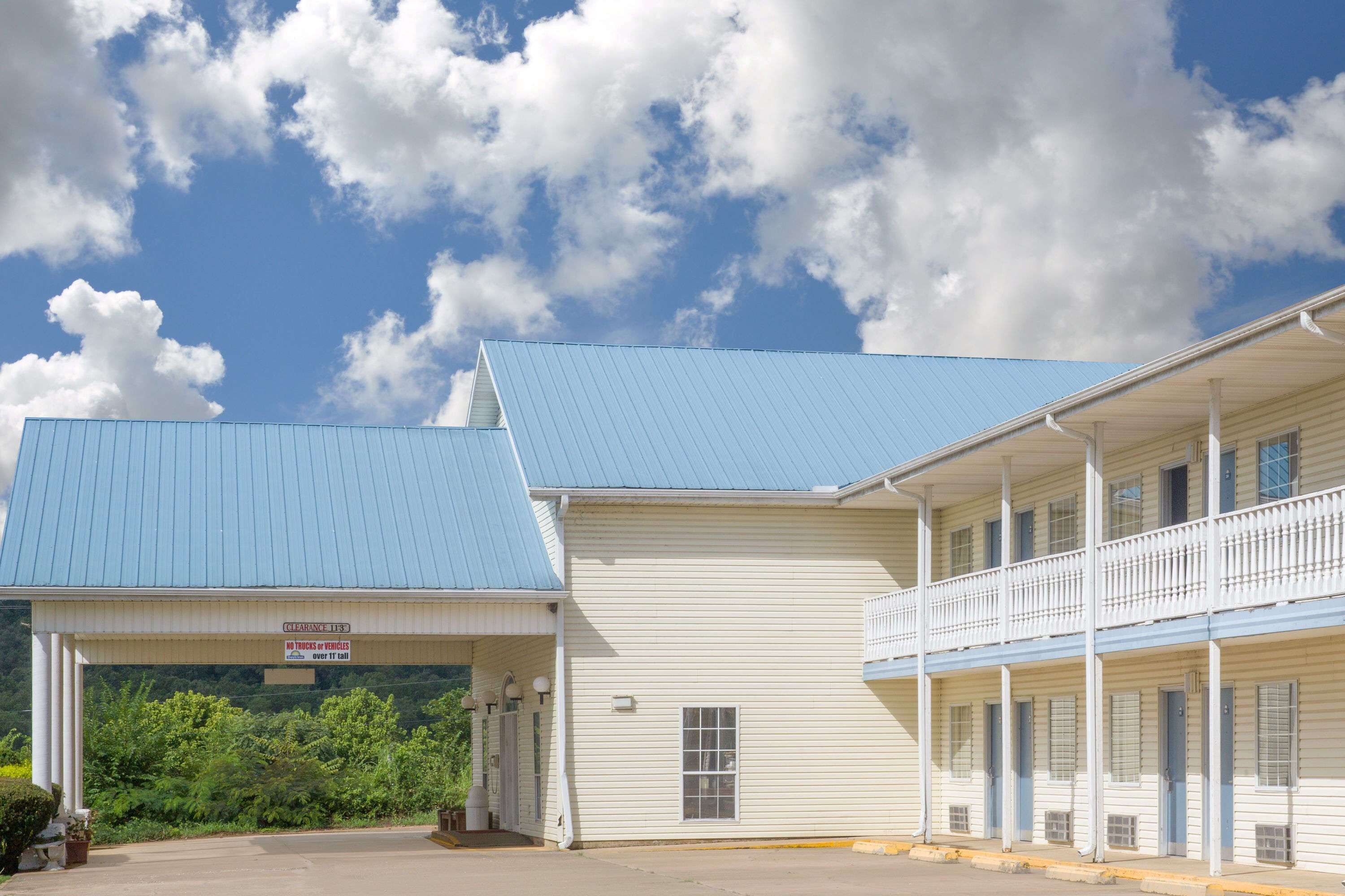 A motel with a blue roof and a covered parking area.