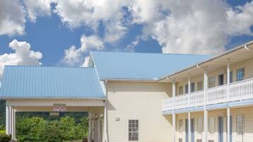 A motel with a blue roof and a covered parking area.