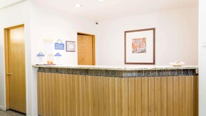 A reception desk with a wooden panel design, a framed picture on the wall, and a sign for Days Inn. - Days Inn by Wyndham Kimball (Kimball)